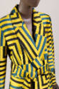 Detail view of yellow, blue and black pantsuit showing shawl collar jacket with superimposed no…