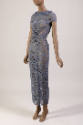 ¾ view of grey short sleeve maxi dress with cowl neck, allover cutouts and knot detail in cente…
