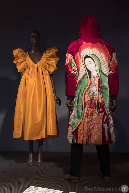 ¡Moda Hoy! exhibition installation view of two mannequins in a yellow dress and a red coat with…