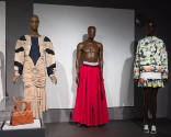 ¡Moda Hoy! exhibition installation view of three dressed mannequins and a brown bag in a case i…