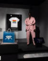 ¡Moda Hoy! exhibition installation view of a t-shirt mounted on the wall, a blue bag in a case …