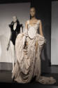 ¡Moda Hoy! exhibition installation view of two mannequins in a black body suit and a white dres…