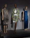 ¡Moda Hoy! exhibition installation view of three mannequins in a black and white dress, green p…