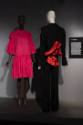 ¡Moda Hoy! exhibition installation view of two mannequins in a dark pink dress and a black and …