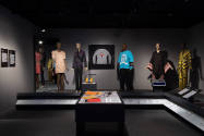 ¡Moda Hoy! exhibition installation view of five dressed mannequins, a sweater in a wall case, a…