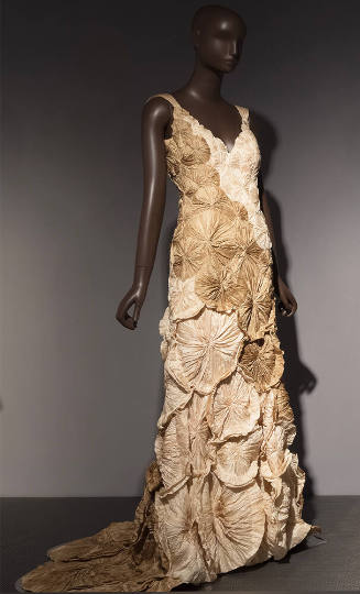 Sleeveless beige and off-white floor length dress covered with circular rosettes 