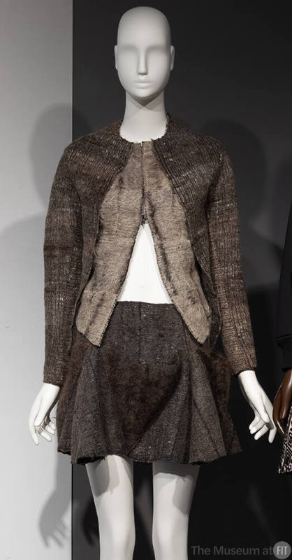 Brown/grey woven collarless long sleeve jacket partially unzipped from bottom and brown woven f…