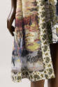Detail view of bottom hem of printed coat and dress ensemble showing zebras, giraffe and landsc…