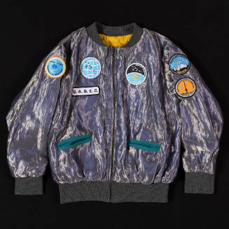 Silver metallic zip front jacket with two green slash pockets and multiple space patches