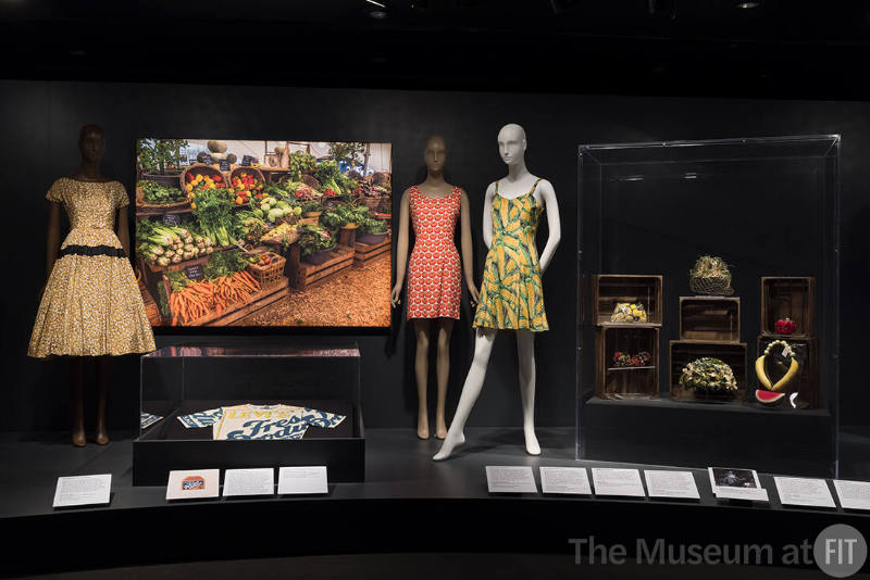 Food & Fashion Left to right: P90.52.1 (peanut dress); Levi Strauss and Co.
“Fresh Produce” t-shirt, circa 1975. Lent by Levi Strauss and Co. Archives; 93.96.2 (tomato dress); 93.96.1 (corn dress); 2003.22.2 (lemon clutch); 86.31.23 (grape hat); 86.104.1 (corn hat); lettuce hat (82.213.75); 97.62.1 (tomato minaudière); 91.258.4 (fruit necklace)