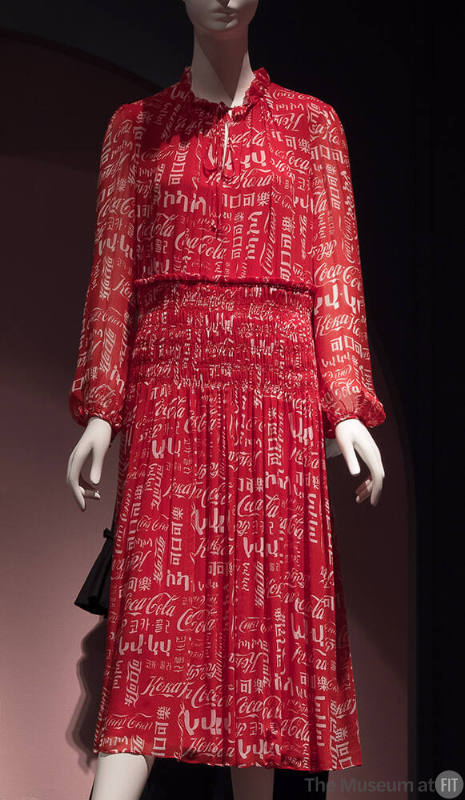 Red sheer long sleeve calf length dress with allover white Coca-Cola logo in multiple languages…