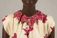Detail of printed red bows on neckline of ivory dress with the same printed bows