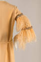 Detail of pale orange long feather sleeve with bands of rhinestones 