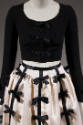 Black long sleeve dress and white knee length skirt with rows of black ribbon bows attached