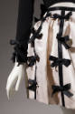 Detail of rows of black ribbon bows attached to white pleated skirt