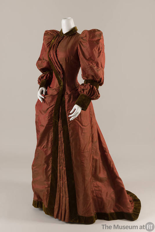 Red silk floor length gown with long puffed sleeves, fitted bodice and green velvet trim, colla…