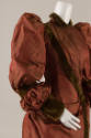 Detail of red silk gown long puffed sleeve, fitted bodice with green velvet trim, collar and cu…