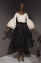 Statement Sleeves exhibition installation view of a mannequin in a white blouse and black skirt…