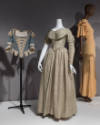 Statement Sleeves exhibition installation view of a corset and two mannequins in dresses in the…