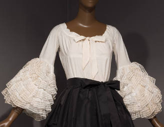 White blouse with bow at center neckline and sleeves with oversize ruffles starting at elbow