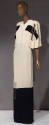 White floor length evening dress with cape-like elbow length sleeves, black bands across either…