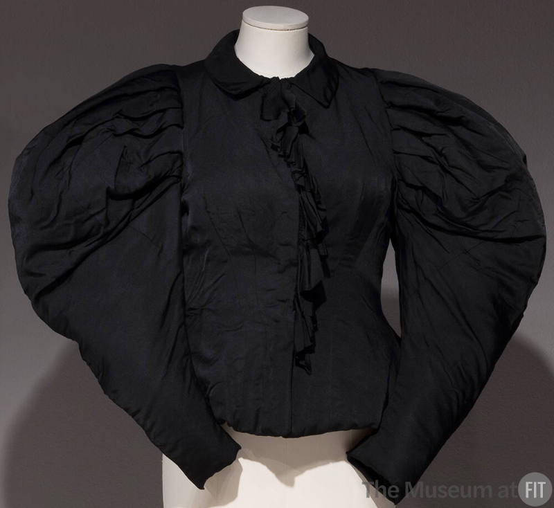 Black top with large puffy sleeves and ruffle down the center front
