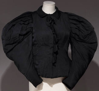 Black top with large puffy sleeves and ruffle down the center front