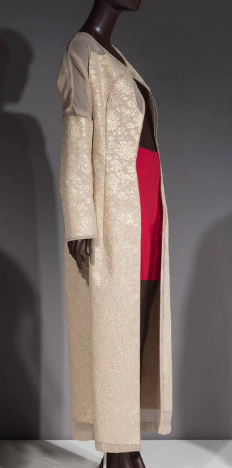 Beige floor length coat with gold floral brocade pattern and sheer insets at shoulders, cuffs a…