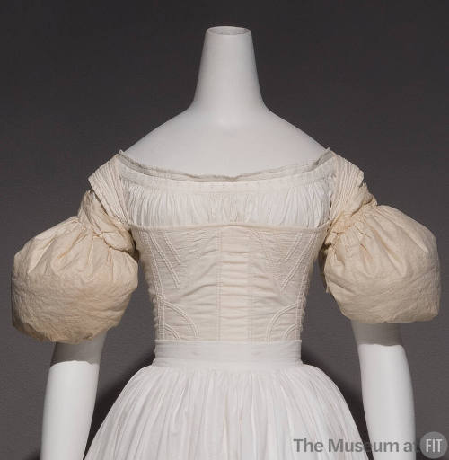 Pair of white sleeve puffs dressed on the upper arms of mannequin with petticoat and corset