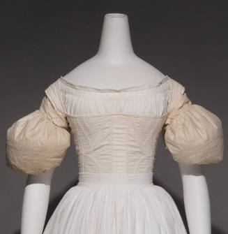 Pair of white sleeve puffs dressed on the upper arms of mannequin with petticoat and corset