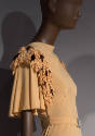 Detail view of pale orange dress showing bands of self petals and purple flowers lining armhole…