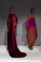 Statement Sleeves exhibition installation view of two mannequins in a dark red tea gown and ora…
