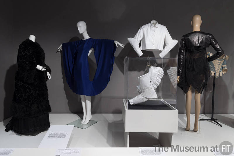 From left to right: black coat, c.1880 (75.227.37); dress by Tom Ford, spring 2013 (2022.65.49); shirt by Lucy Jones, 2017 (2017.60.1); sleeves by Lucy Jones, 2017 (case, 2017.60.3 and 2017.60.2); ensemble by Helmut Lang, fall 2003 (2009.32.17); and corset, c.1770 (P82.1.16)