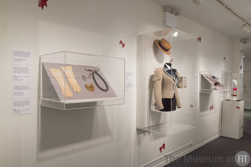 From left to right: Cream gloves, 1950s (P91.65.2); Trifari pin, 1944 (86.104.3); gold pin, 1980s (2020.10.4); Lanvin necklace, Fall 2006 (2007.10.2); straw hat, 1910-1915 (P88.73.1) and linen jacket, c.1896 (P84.26.1)