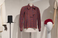 Untying the Bow exhibition installation view of a red, blue and brown blouse with a large neck …