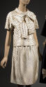 Two-piece white dress with black polka dots, blouse has large bow tie collar