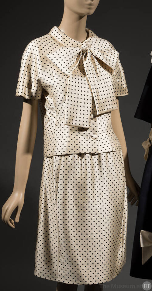 Two-piece white dress with black polka dots, blouse has large bow tie collar