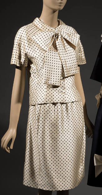 Two-piece white dress with black polka dots, blouse has large bow tie collar