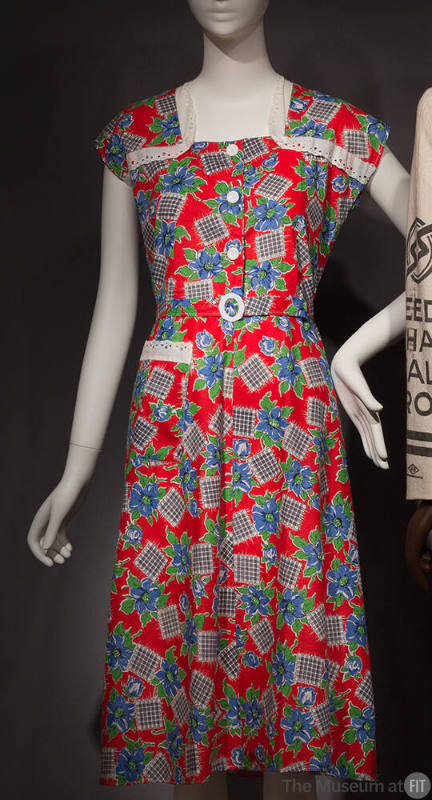 Red sleeveless dress with blue and green floral and black and white check print, white lace tri…