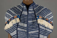 Detail view of trim at shoulders: off-white fringe, blue pailettes, mirrors with orange ties an…