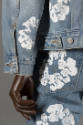 Detail view of jacket sleeve with button closing and back pocket of jeans 
