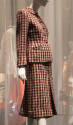 Gallery view of a red, grey and blue checked suit with five center buttons, round scalloped col…