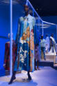 Africa’s Fashion Diaspora exhibition installation view of a mannequin in a blue tent dress with…