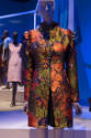 Africa’s Fashion Diaspora exhibition installation view of a mannequin in an orange, green and p…