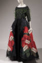 Black floor length dress with green feathers all over bodice and large rose and razor blade pri…