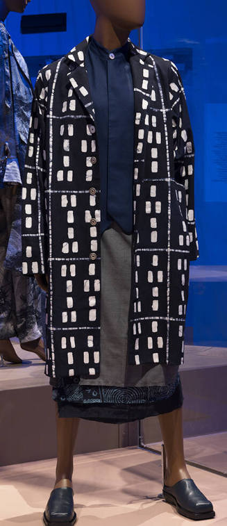 Blue knee length button front coat with white geometric print, blue vest and wrap skirt with bl…
