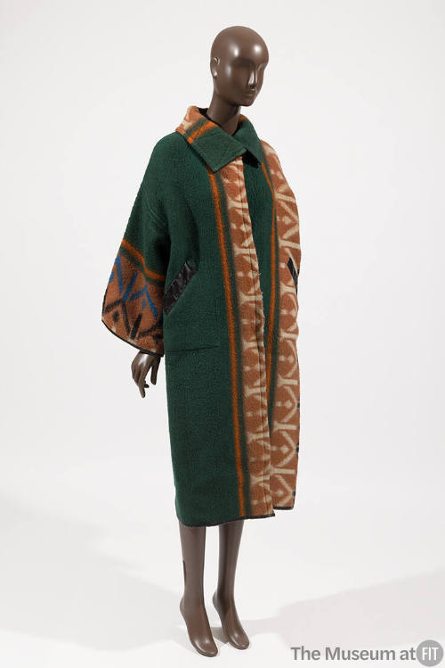 Green coat with vertical orange, white, black and blue geometric designs and oversize collar