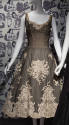 Cream evening dress with black dotted net and cream floral and ribbon designs over top, sleevel…