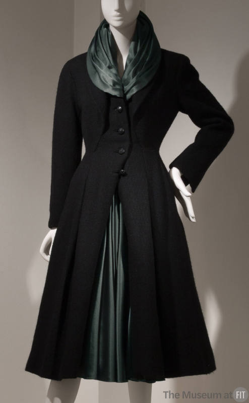 Black calf length button front coat with inverted pleats, flared from the waist, v-neck dressed…