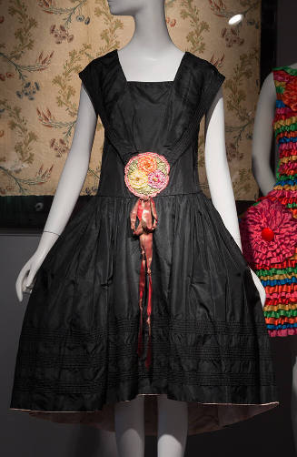 Black knee length dress with large collar meeting at front waist at large multicolor ribbon flo…